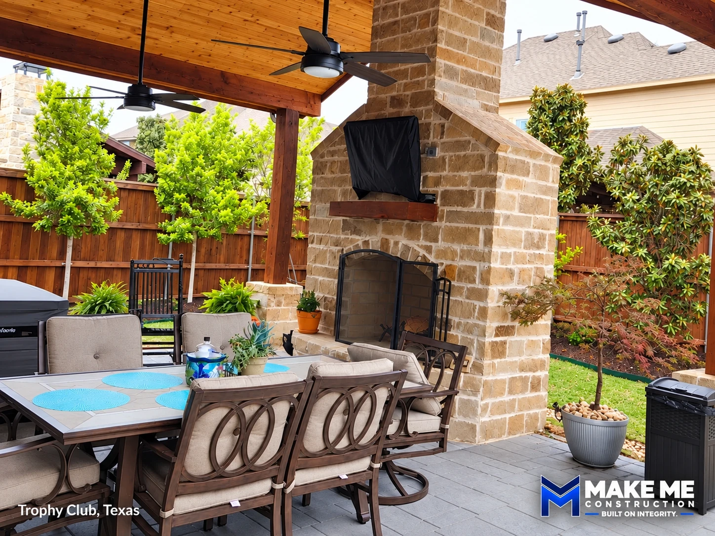 Covered patio with wood ceiling, fans and stone fireplace — Trophy Club, Texas